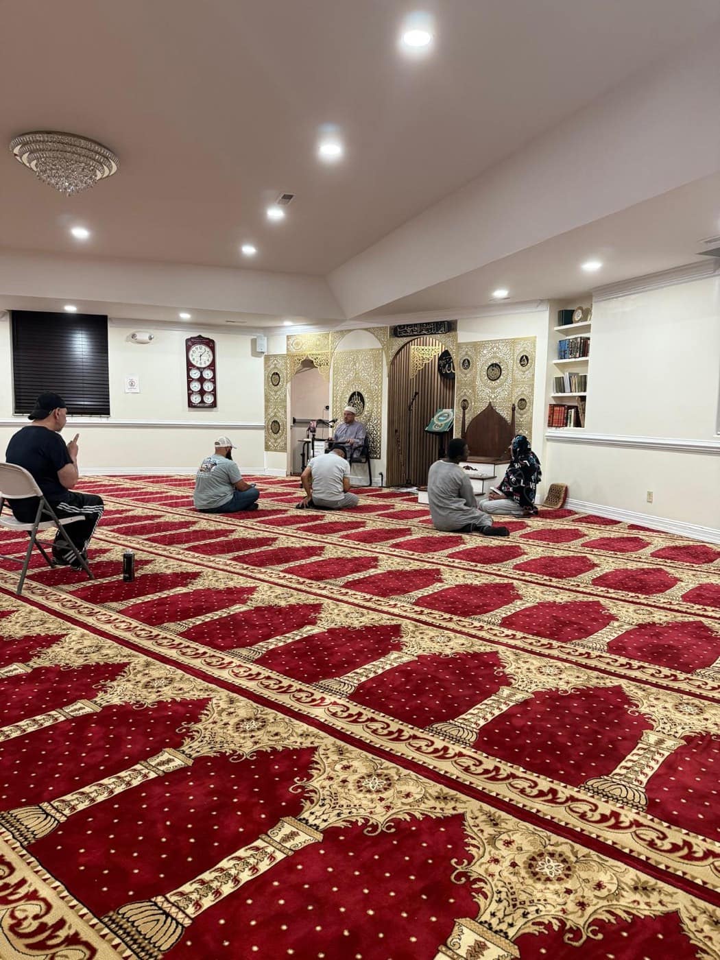 The Imam leading the Qur'an circle after Fajr, a few worshippers seated on the red prayer carpet