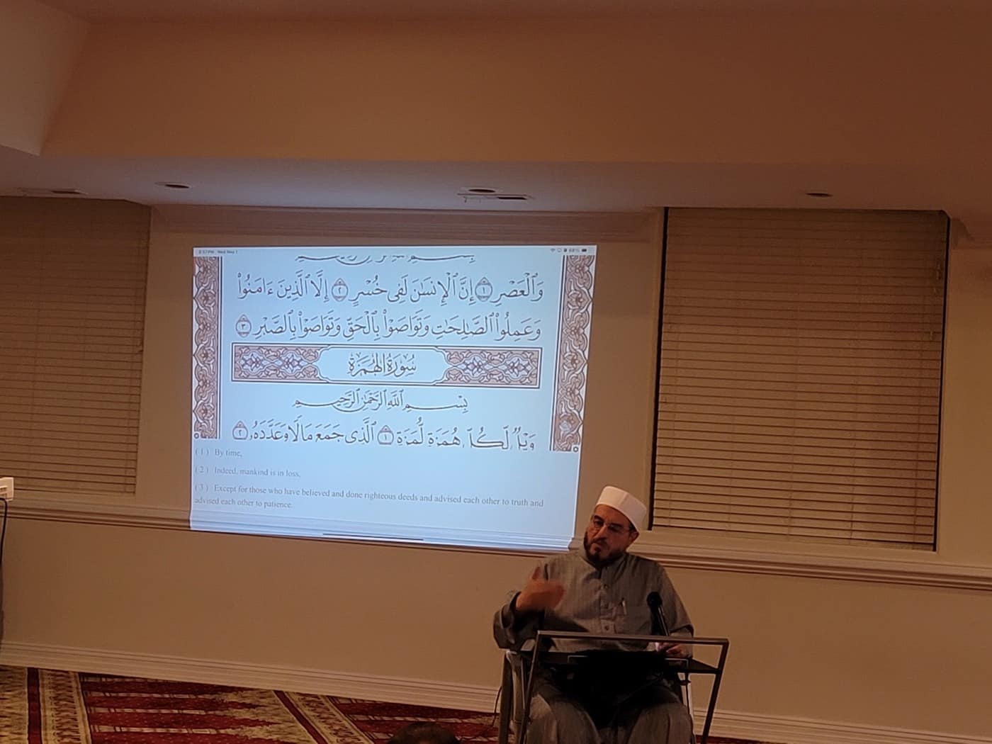 The Imam teaching the Qur'an Suras Interpretation class, with Surah Al-Asr projected on the wall