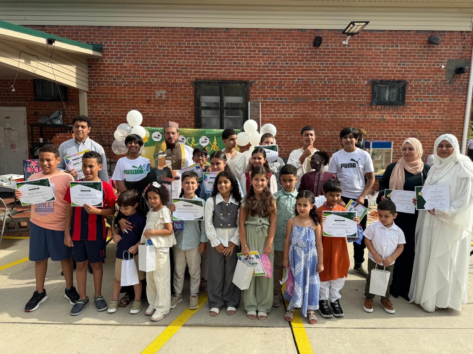 Sunday School children holding their certificates outside the masjid on Eid al-Adha and School Graduation Day